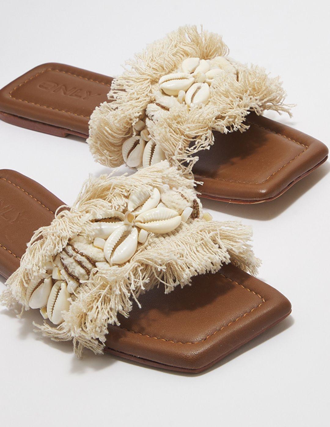 Sandalia plana color crema con flecos y conchas